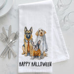 Load image into Gallery viewer, A white kitchen towel with a watercolor illustration of three dogs dressed in Halloween costumes, with the text 'HAPPY HALLOWEEN' printed below. The towel is styled on a white marble surface with silver cutlery, plates, and wine glasses.

