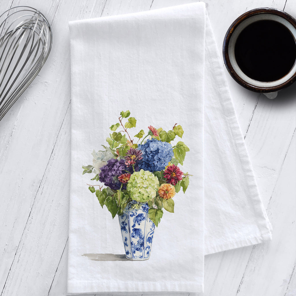 Floral design on a white towel with a cup of coffee and whisk in the background