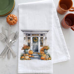 Load image into Gallery viewer, A white kitchen towel with a printed autumn porch illustration, styled on a white marble surface with silverware, green plates, orange mugs, and a small decorative pumpkin.
