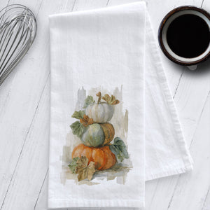 Stacked pumpkin watercolor tea towel on white cotton flour sack, autumn kitchen decor featuring heirloom pumpkins in orange and sage.